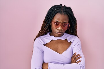 African woman with braided hair standing over pink background skeptic and nervous, disapproving...