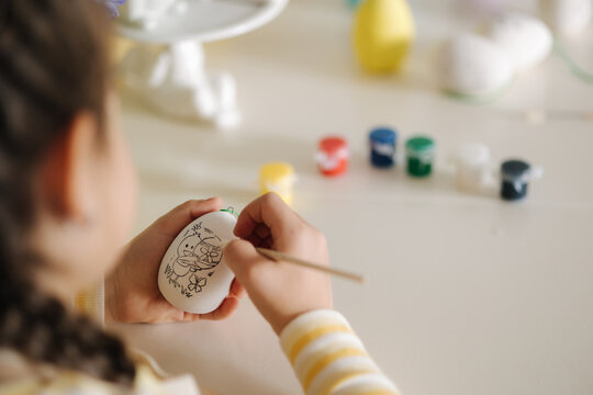 First person view of little girl painting easter egg