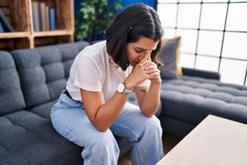 Young woman stressed sitting on sofa at home