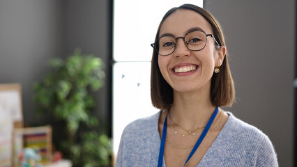 Young beautiful hispanic woman teacher smiling confident standing at kindergarten
