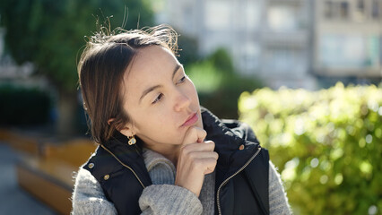Young beautiful hispanic woman standing with doubt expression at park
