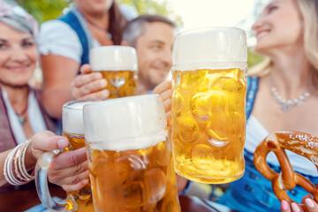 Group clinking with beers in Bavarian beergarden - 585440795