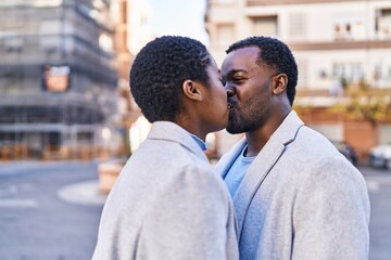 Man and woman couple standing together kissing at street