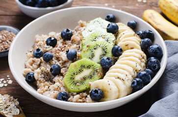 Oatmeal Bowl with Blueberry, Banana and Kiwi, Oat Porridge in a Bowl on Rustic Background, Healthy Snack or Breakfast
