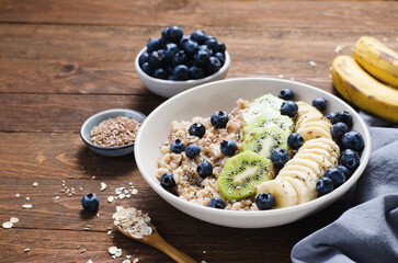 Oatmeal Bowl with Blueberry, Banana and Kiwi, Oat Porridge in a Bowl on Rustic Background, Healthy Snack or Breakfast