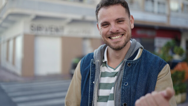 Young caucasian man smiling confident asking to come at street