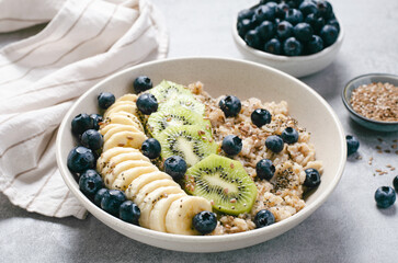 Oatmeal Bowl with Blueberry, Banana and Kiwi, Oat Porridge in a Bowl on Bright Background, Healthy Snack or Breakfast