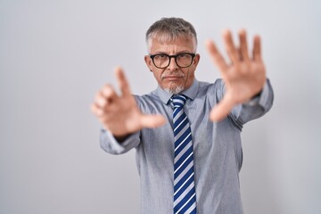 Hispanic business man with grey hair wearing glasses doing frame using hands palms and fingers, camera perspective