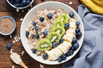 Oatmeal Bowl with Blueberry, Banana and Kiwi, Oat Porridge in a Bowl on Rustic Background, Healthy Snack or Breakfast