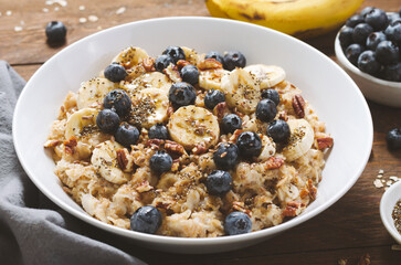 Oatmeal Bowl, Oat Porridge with Blueberry, Banana and Pecans in a Bowl on Wooden Background, Healthy Snack or Breakfast