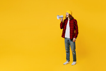 Full body young man wearing red checkered shirt white t-shirt hat hold in hand megaphone scream announces discounts sale Hurry up isolated on plain yellow background studio portrait Lifestyle concept