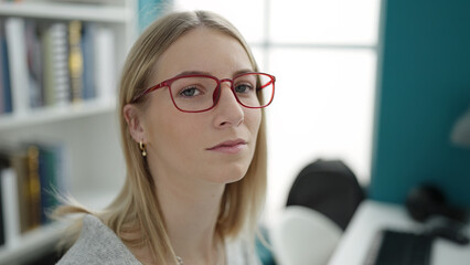 Young blonde woman sitting with serious expression at library university