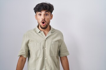 Arab man with beard standing over white background afraid and shocked with surprise and amazed expression, fear and excited face.