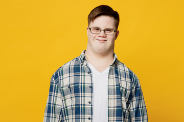 Young smiling fun cheerful happy positive man with down syndrome wearing glasses blue casual clothes looking camera isolated on pastel plain yellow color background. Genetic disease world day concept.