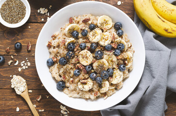 Oatmeal Bowl, Oat Porridge with Blueberry, Banana and Pecans in a Bowl on Wooden Background, Healthy Snack or Breakfast