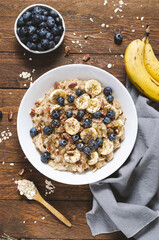 Oatmeal Bowl, Oat Porridge with Blueberry, Banana and Pecans in a Bowl on Wooden Background, Healthy Snack or Breakfast