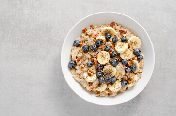 Oatmeal Bowl, Oat Porridge with Blueberry, Banana and Pecans in a Bowl on Bright Background, Healthy Snack or Breakfast