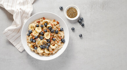 Fototapeta na wymiar Oatmeal Bowl, Oat Porridge with Blueberry, Banana and Pecans in a Bowl on Bright Background, Healthy Snack or Breakfast