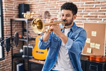 Young arab man musician playing trumpet at music studio © Krakenimages.com