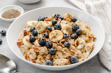 Oatmeal Bowl, Oat Porridge with Blueberry, Banana and Pecans in a Bowl on Bright Background, Healthy Snack or Breakfast