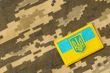 Pixeled digital military camouflage fabric with ukrainian flag and coat of arms on chevron in blue...