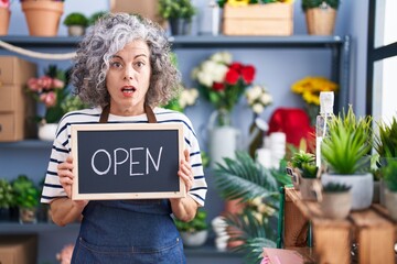 Middle age woman with grey hair working at florist with open sign skeptic and nervous, frowning upset because of problem. negative person.