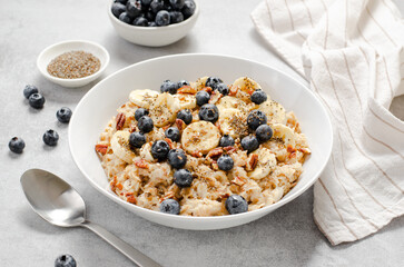 Oatmeal Bowl, Oat Porridge with Blueberry, Banana and Pecans in a Bowl on Bright Background, Healthy Snack or Breakfast