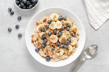 Oatmeal Bowl, Oat Porridge with Blueberry, Banana and Pecans in a Bowl on Bright Background, Healthy Snack or Breakfast