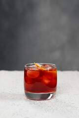 Closeup glass of cosmopolitan cocktail decorated with orange at greay wall background with copyspace.