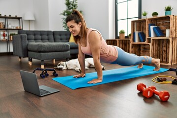 Obraz premium Young woman smiling confident having online abs exercise class at home