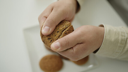 Young hispanic man holding cookie at home