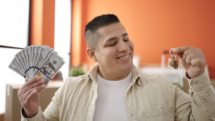 Young hispanic man smiling confident holding money and keys at new home