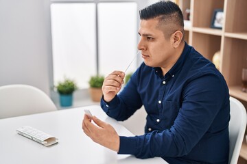 Young latin man sitting on table make antigen test at home
