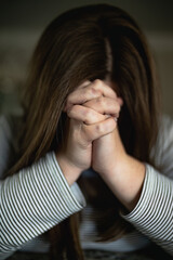woman praying with hands clasped in front of face. Focus on prayer hands concept for faith, spirituality, religion, Christianity
