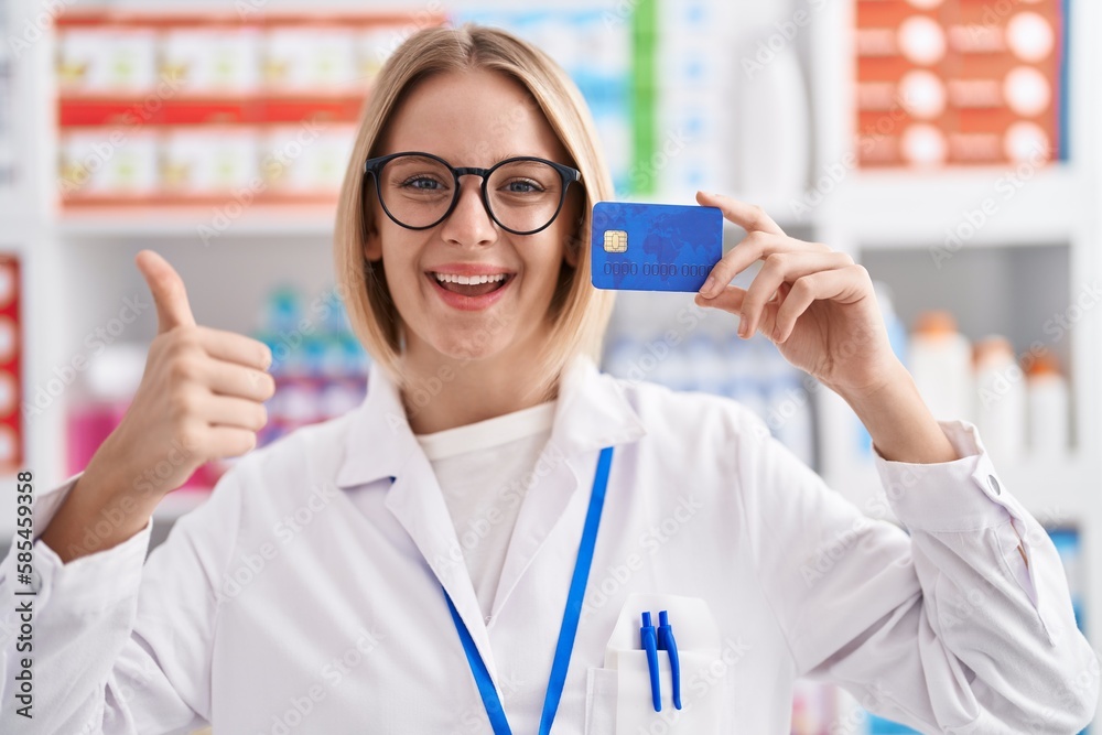 Sticker young caucasian woman working at pharmacy drugstore holding credit card smiling happy and positive, 