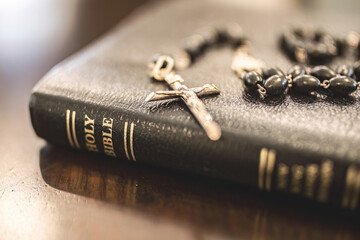 Catholic rosary and crucifix laying on leather bound holy Bible close up, Christian, Christianity,...