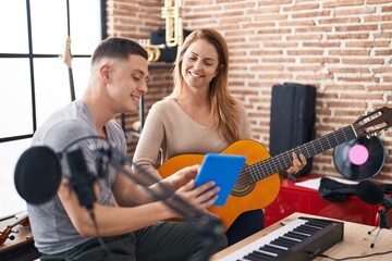 Man and woman musicians having classic guitar lesson using touchpad at music studio
