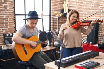 Man and woman musicians playing violin and classical guitar at music studio