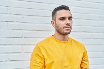 Young hispanic man looking to the side with serious expression over isolated white background