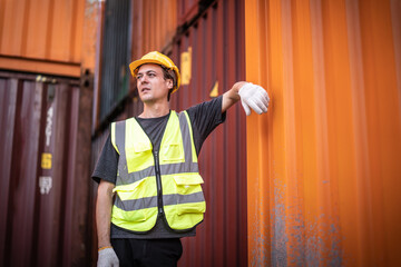 Caucasian warehouse worker in uniform with hard hat standing in container port terminal. Area logistics import export and shipping.