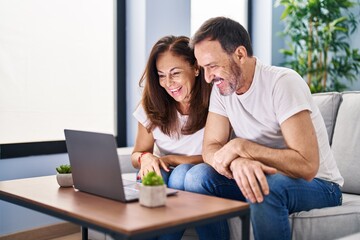 Middle age man and woman couple having video call sitting on sofa at home