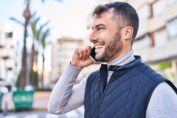 Young hispanic man smiling confident talking on the smartphone at street
