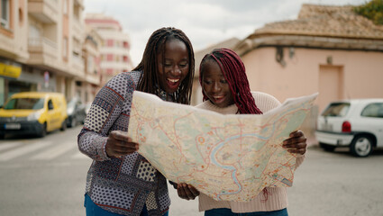 Two african american friends smiling confident looking city map at street