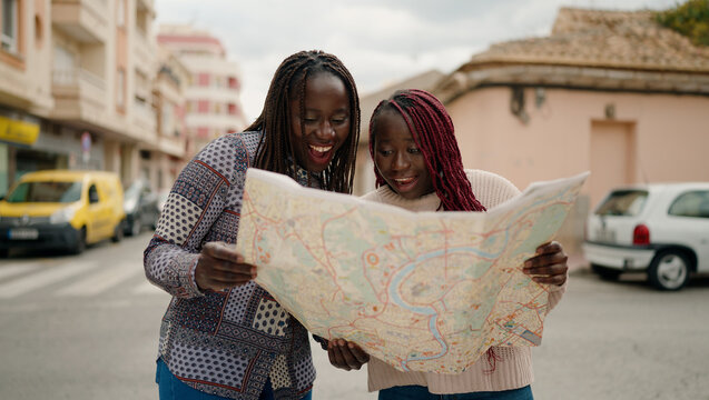 Two african american friends smiling confident looking city map at street - Powered by Adobe