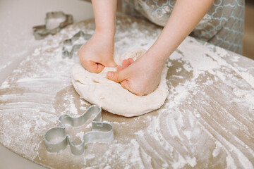 happy little girl making dough in the kitchen. a small child learns to cook food or bake yeast dough with his hands at home