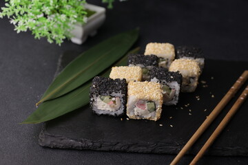 Sushi rolls on black background with salmon cheese and fish