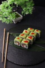 Sushi rolls on black background with salmon cheese and fish