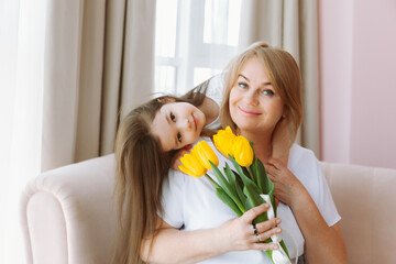 Fototapeta na wymiar A little granddaughter gives her grandmother a bouquet of tulips. A happy family. The concept of gratitude, love, well-being