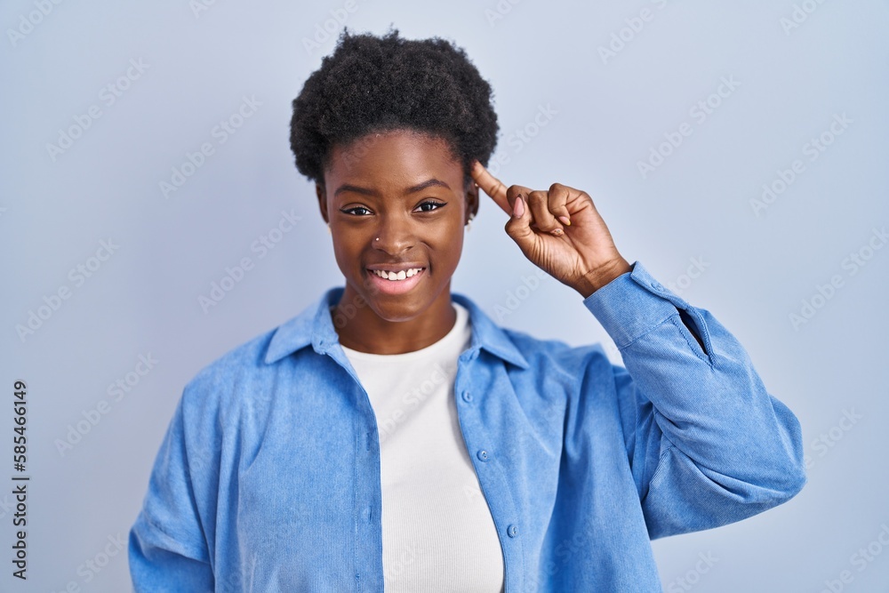 Sticker African american woman standing over blue background smiling pointing to head with one finger, great idea or thought, good memory