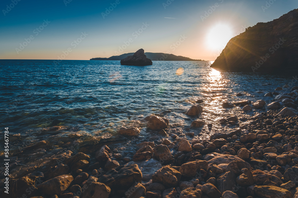 Wall mural rocky pebble sea beach with rocks at sunset, beautiful landscape with sunshine bokeh